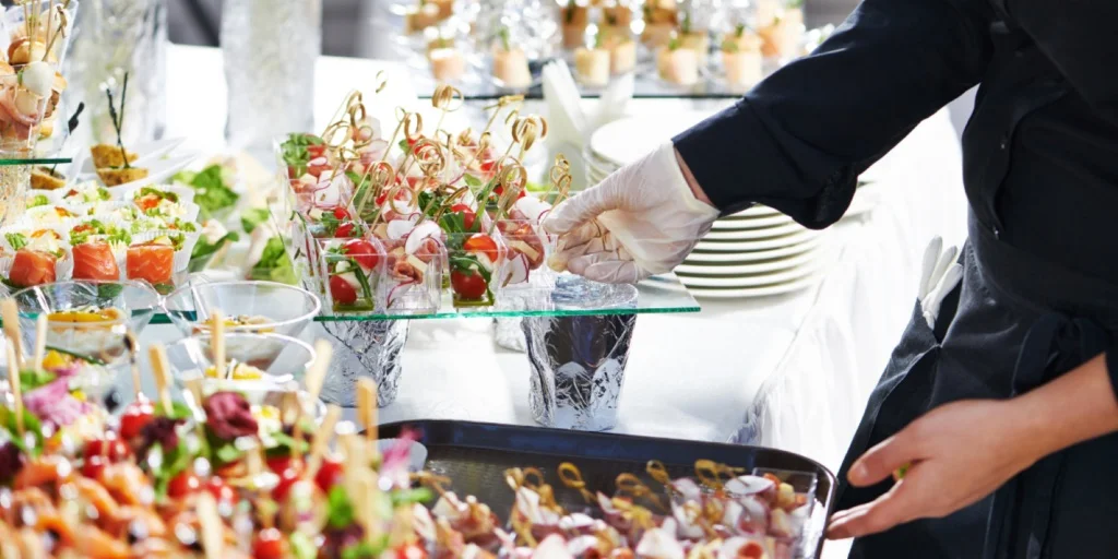 Serveur ganté qui dresse des bouchées sur un buffet