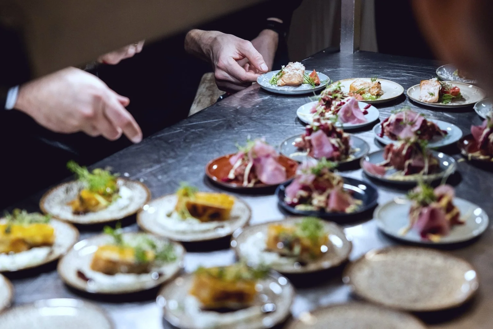 Équipe de cuisine qui dresse des assiettes en série au passe